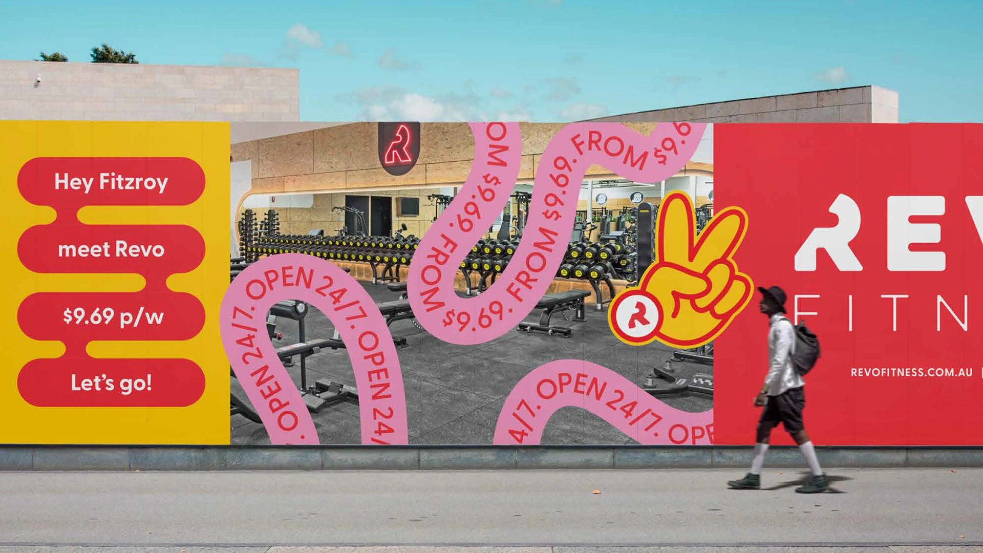 Revo Fitness outdoor mural mockup viewed from street level showing the large-scale brand campaign on a building with pedestrians walking by