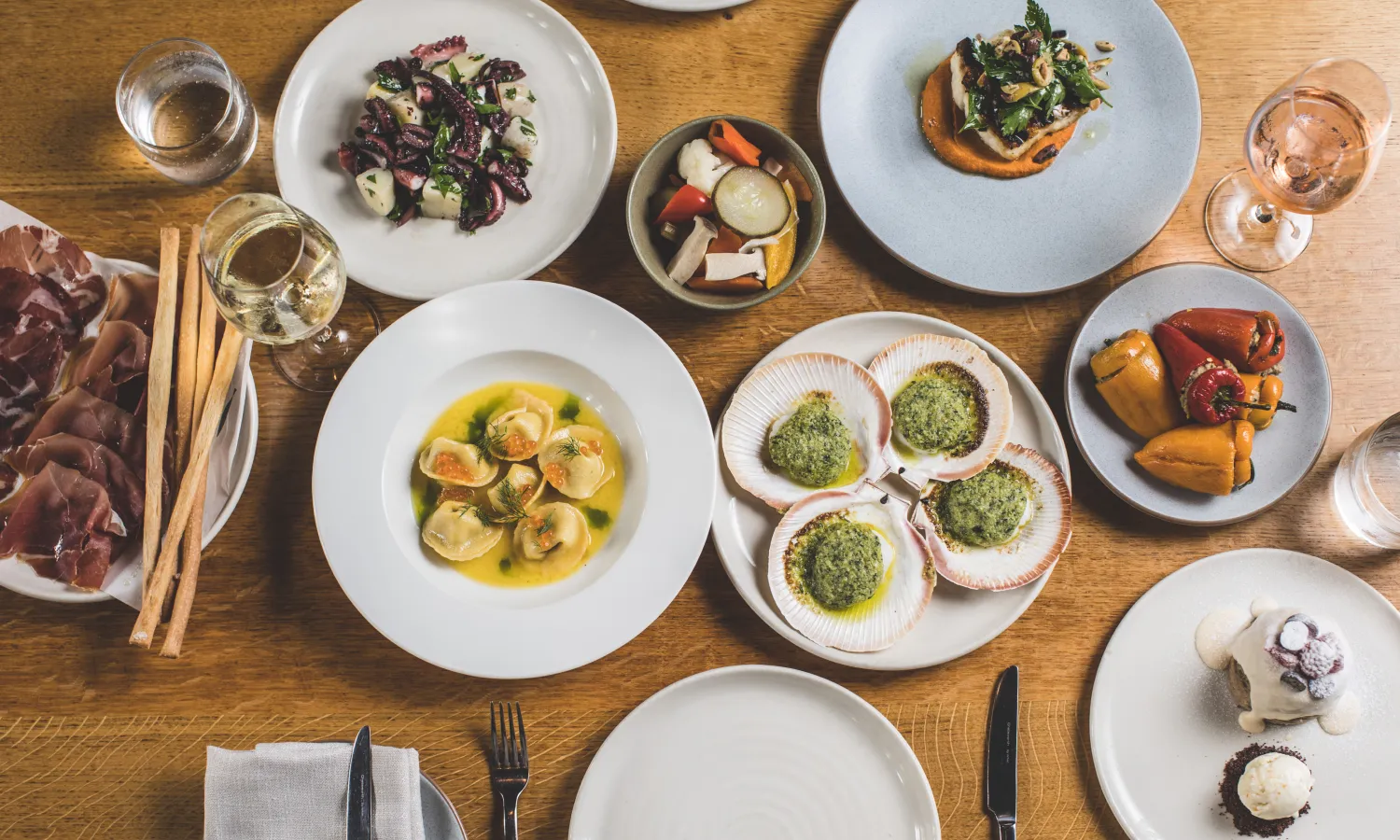 Overhead view of multiple Italian-Mediterranean dishes spread across a dining table